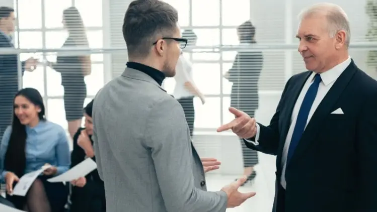 Executive assistant talking with C-suite member at an office setting.