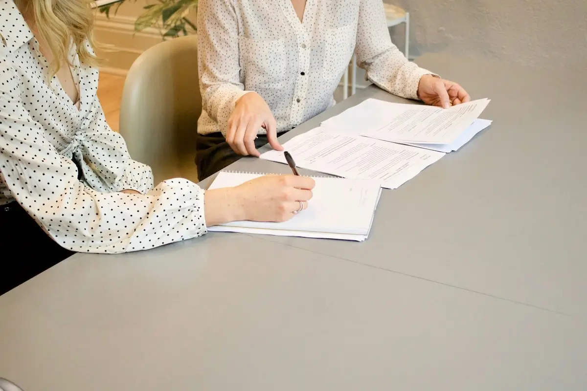 Legal assistants working together on a desk, with some documents.